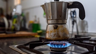 A coffee pot sits on a gas burner.