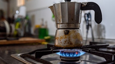 A coffee pot sits on a gas burner.