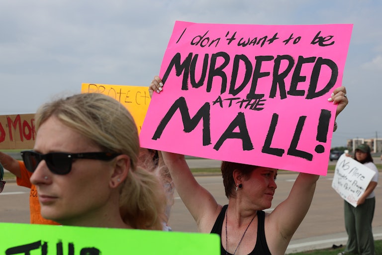 A gun violence protester holds a sign reading "I don't want to be murdered at the mall." Others around her hold signs as well.