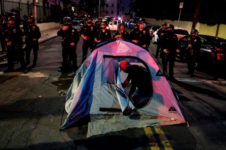 A man sets up a tent in front of police during a protest ahead of a planned and announced clean-up of a homeless encampment.