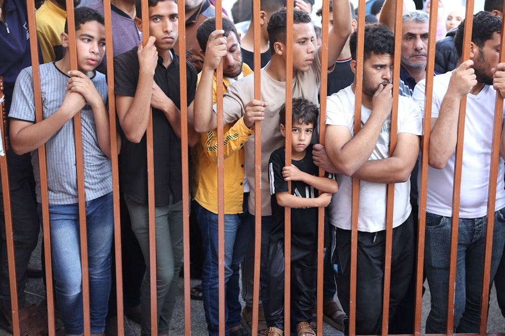 Palestinians wait to collect the bodies of their relatives outside the Nasser hospital