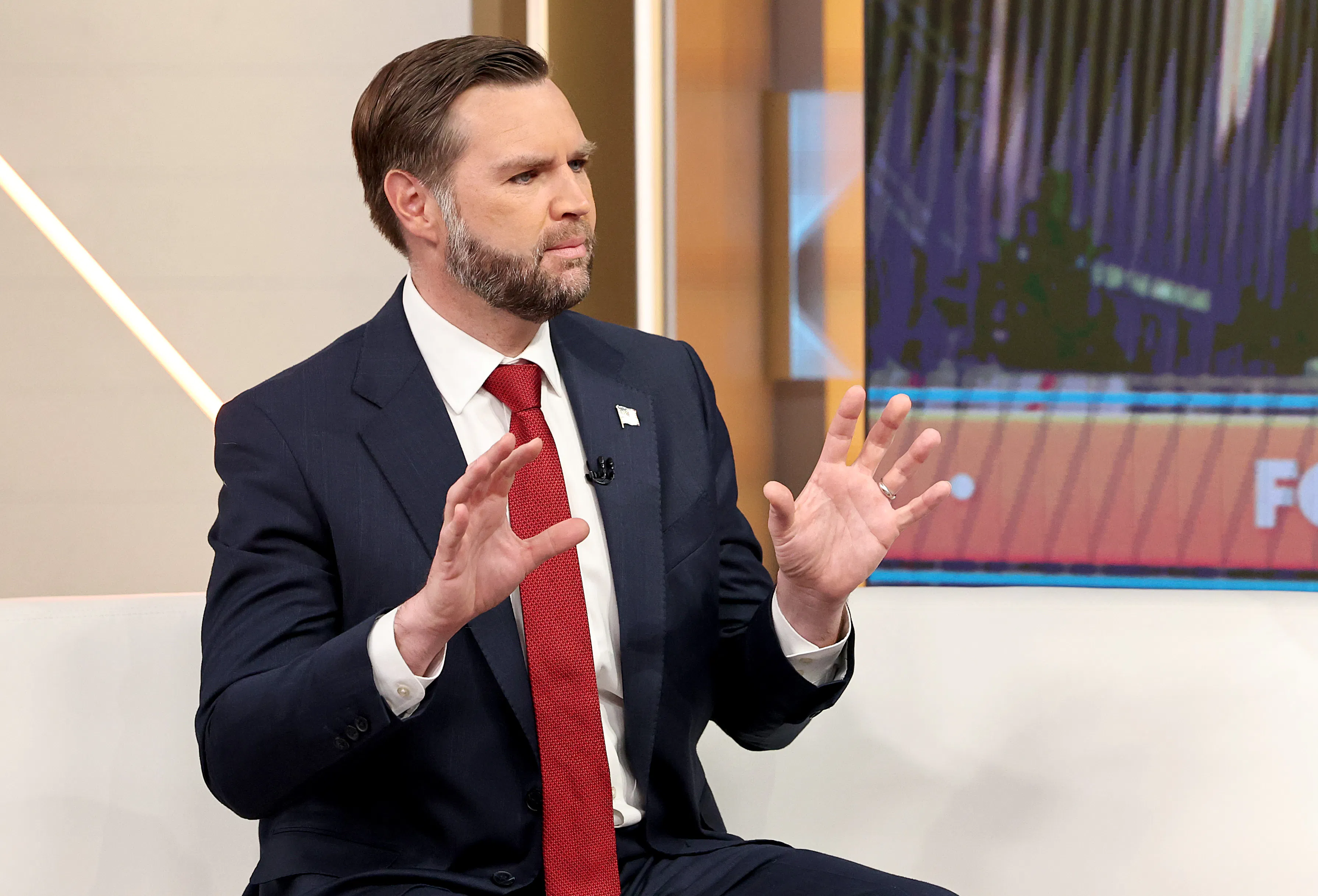 JD Vance holds up both hands while talking