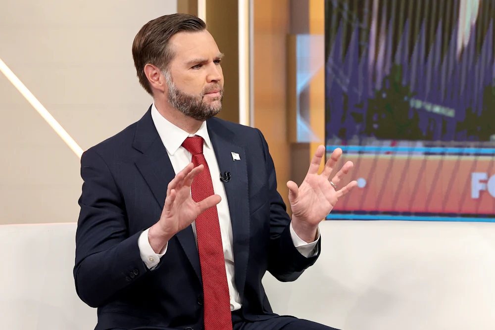 JD Vance holds up both hands while talking