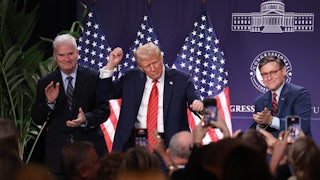 Trump holds his fists up, dancing in front of a crowd, flanked by Tom Emmer and Mike Johnson.