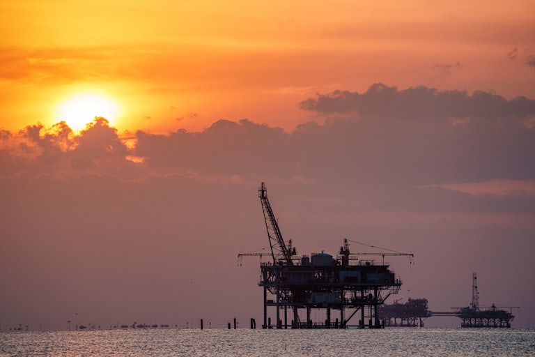 An oil rig against the setting sun.