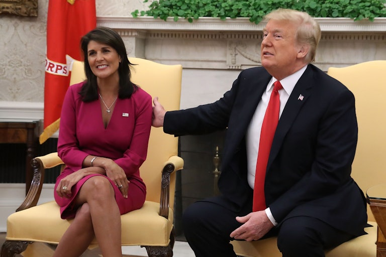 Donald Trump puts a hand on Nikki Haley's shoulder. She smiles toward the camera, and he makes a weird face.
