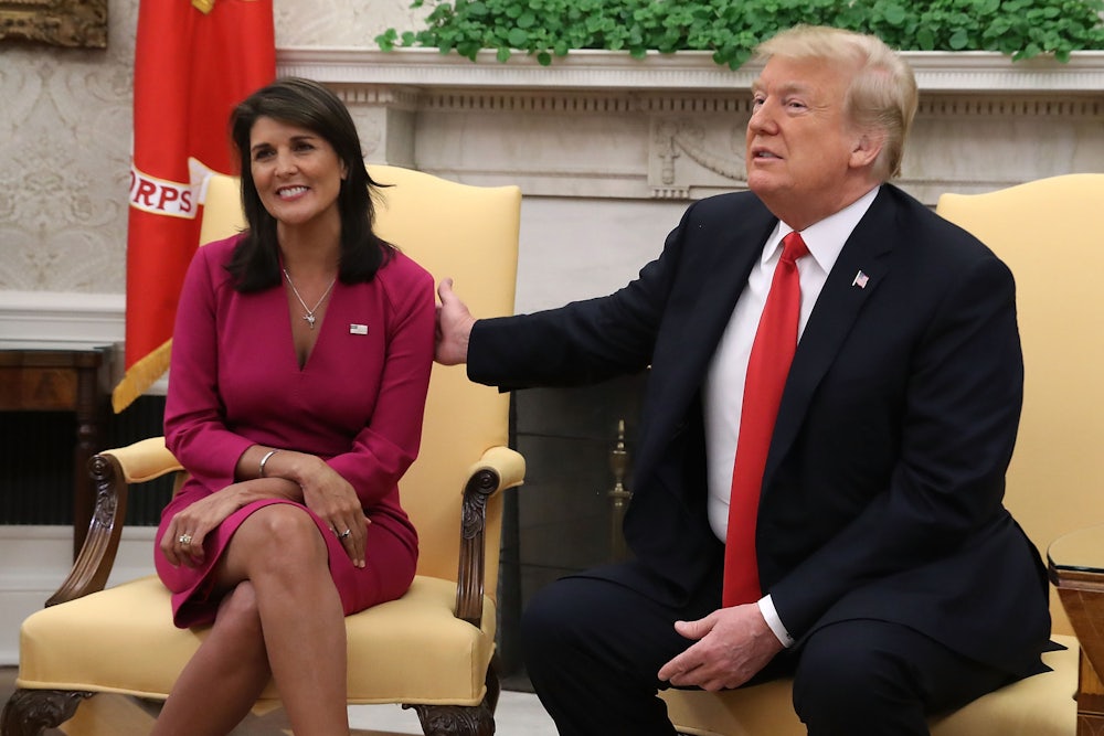Donald Trump puts a hand on Nikki Haley's shoulder. She smiles toward the camera, and he makes a weird face.