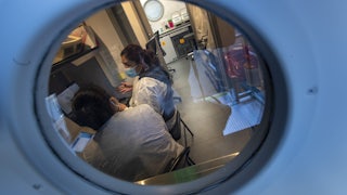 Two lab staff members sit confer while sitting in front of screens.
