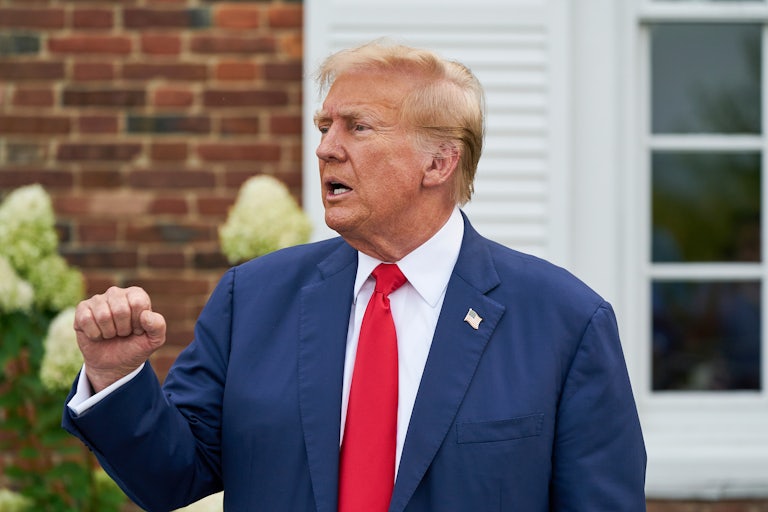 Donald Trump holds up his fist and speaks during a press conference