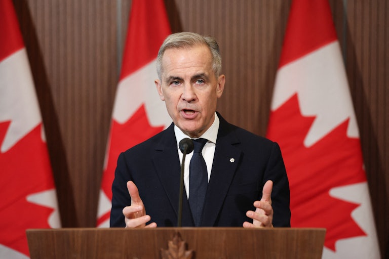 Canadian Prime Minister Mark Carney gestures while speaking at a podium