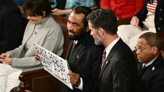 Representative Al Green holds a sign reading “Black People Aren’t Apes” during President Donald Trump’s State of the Union address.