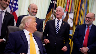 President Donald Trump laughs while seated at his desk in the Oval Office of the White House, while Office of Management and Budget Director Russell Vought, Energy Secretary Chris Wright, Commerce Secretary Howard Lutnick, and White House Office of Science and Technology Policy Director Michael Kratsios stand behind him.