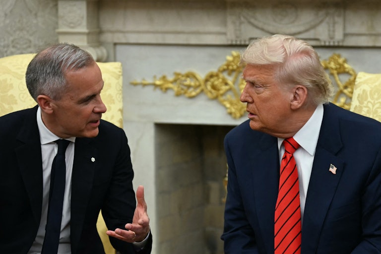 Canadian Prime Minister Mark Carney gestures while speaking to Donald Trump, as they sit next to each other in the Oval Office