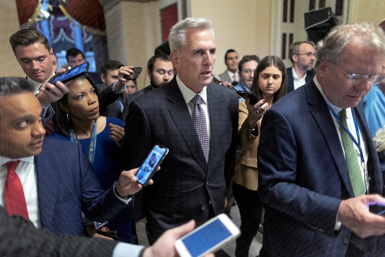Kevin McCarthy walks as a gaggle of reporters surrounds him