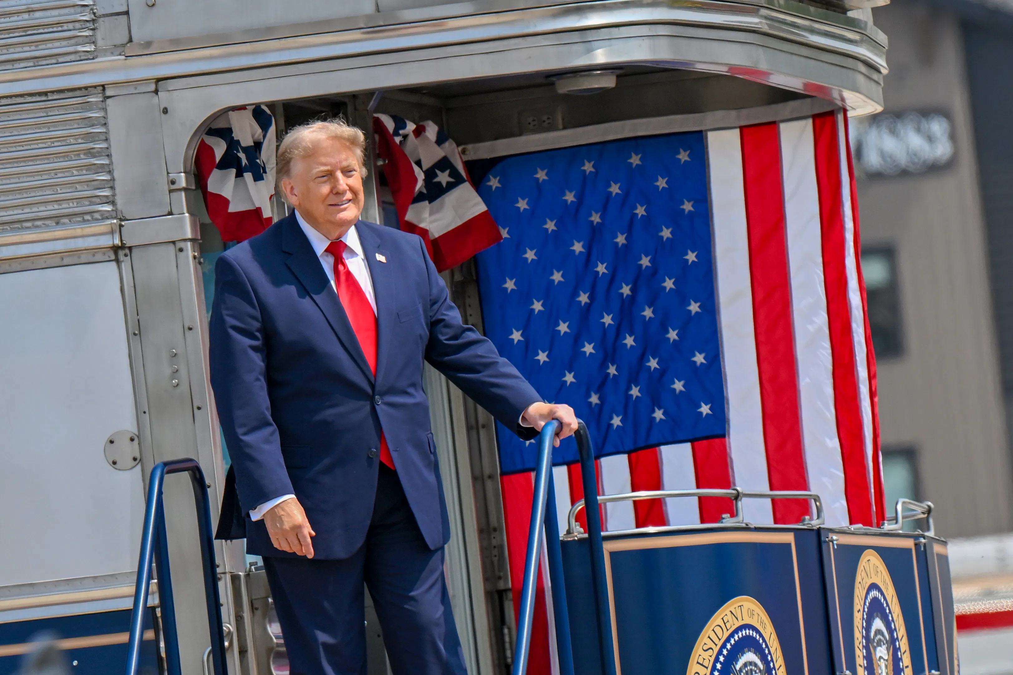 Donald Trump stands on a ledge with lots of American flags