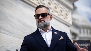 Representative Cory Mills wears sunglasses and speaks outside the Capitol.
