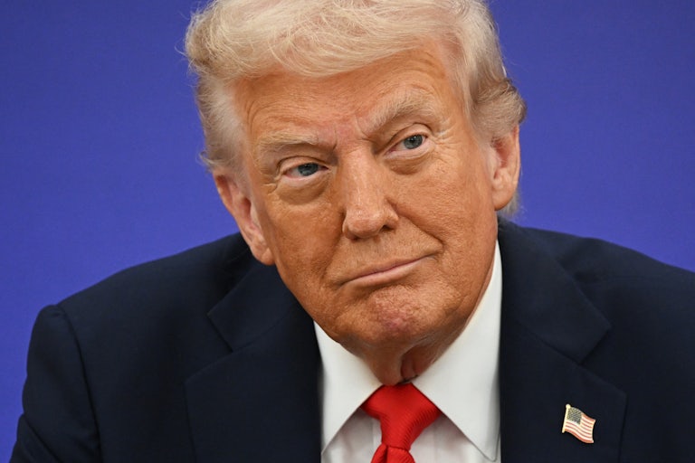 Donald Trump smiles while sitting in a press conference