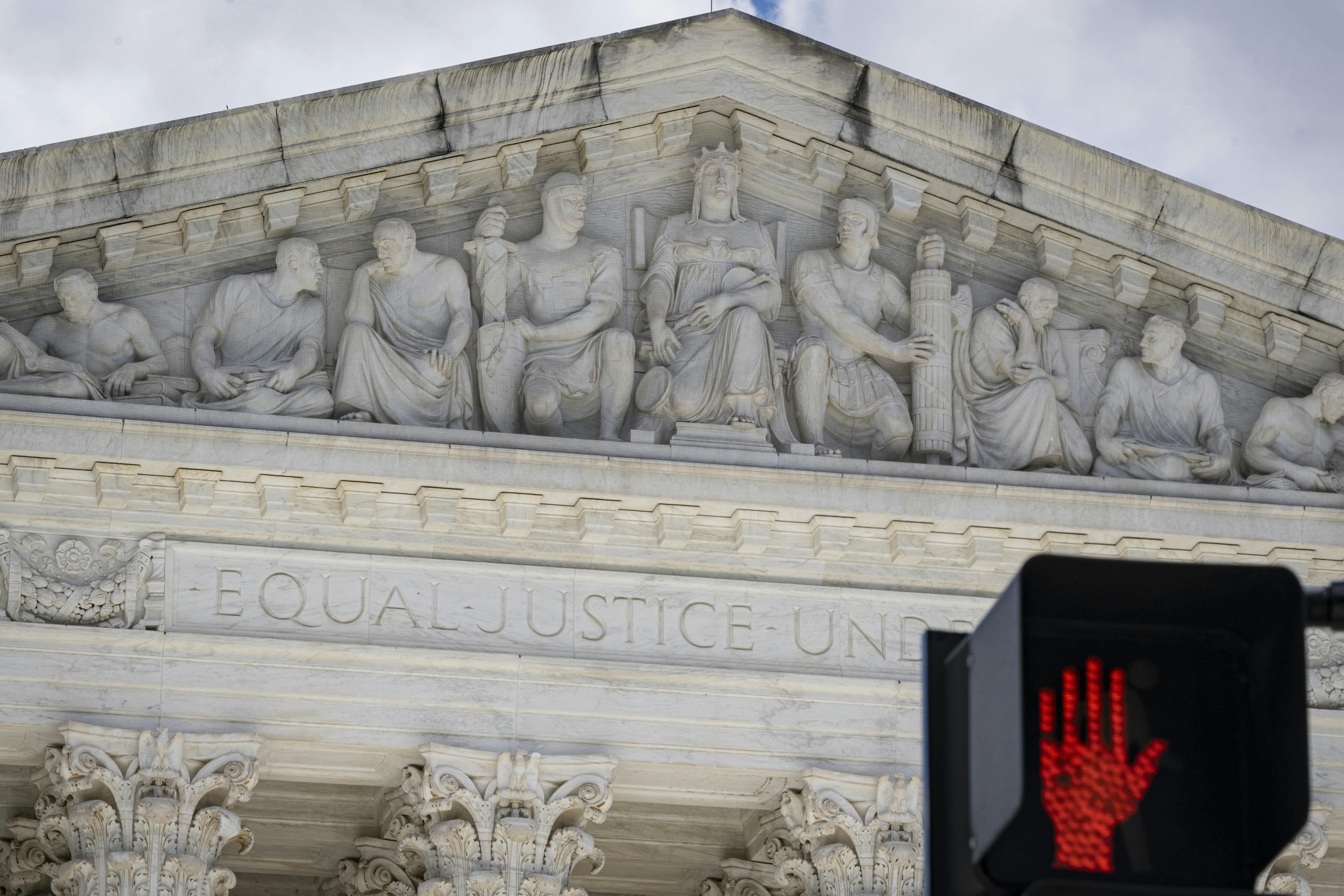 The Supreme Court building with a red traffic signal in front of it.