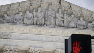 The Supreme Court building with a red traffic signal in front of it.
