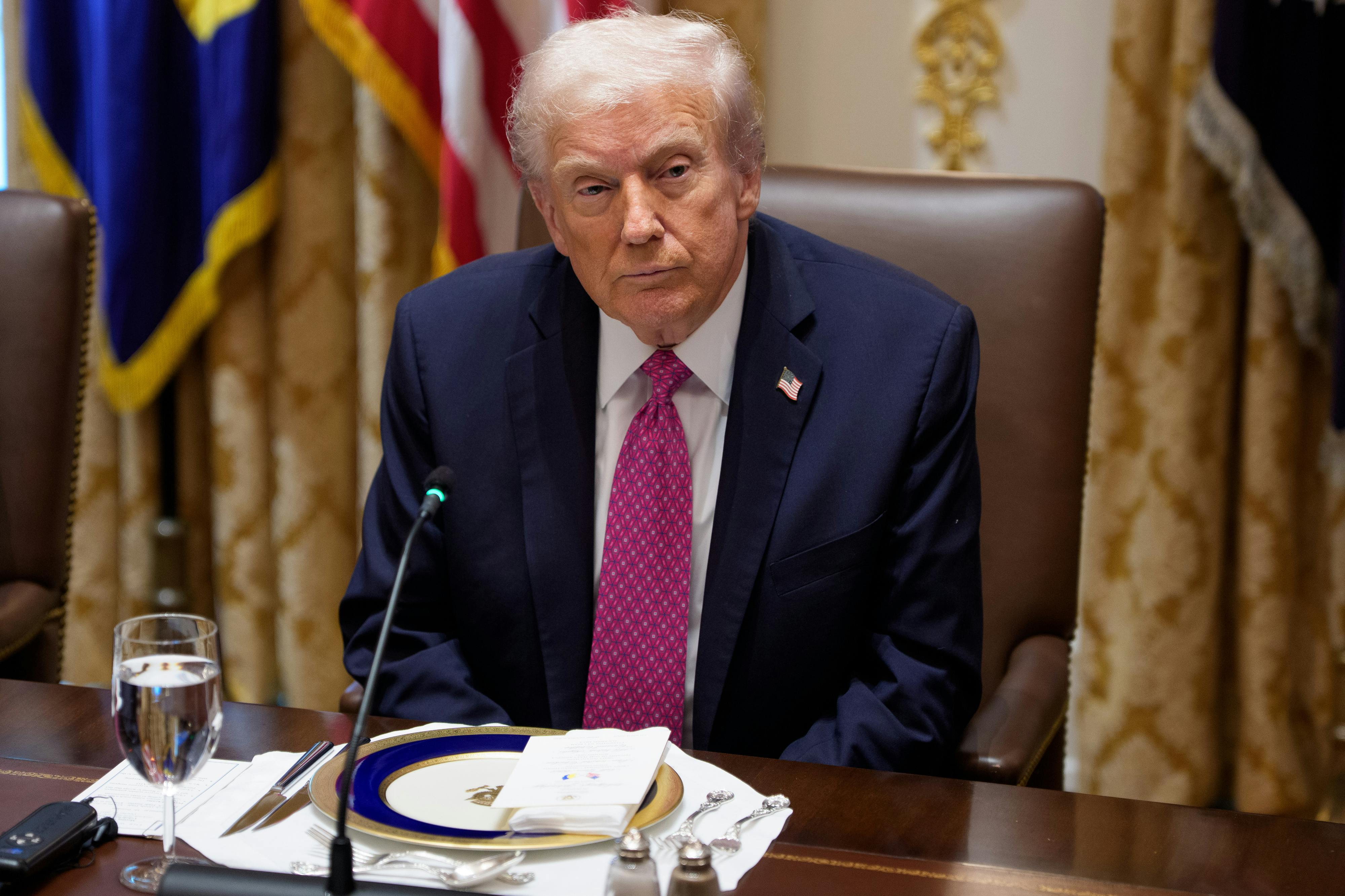 Donald Trump sits at a table with a setting for a formal meal