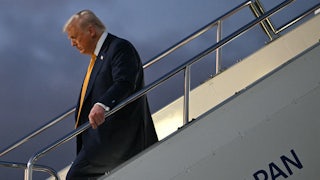 Donald Trump looks down while walking down a flight of stairs off an airplane
