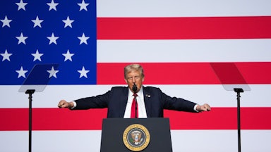 Donald Trump holds his fists out to the side while speaking to military leaders at Quantico