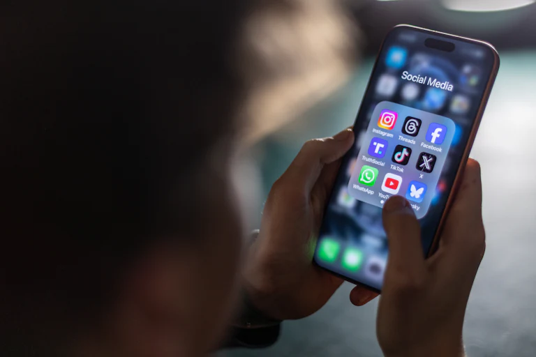 A person holds a smartphone with social media apps on the screen.