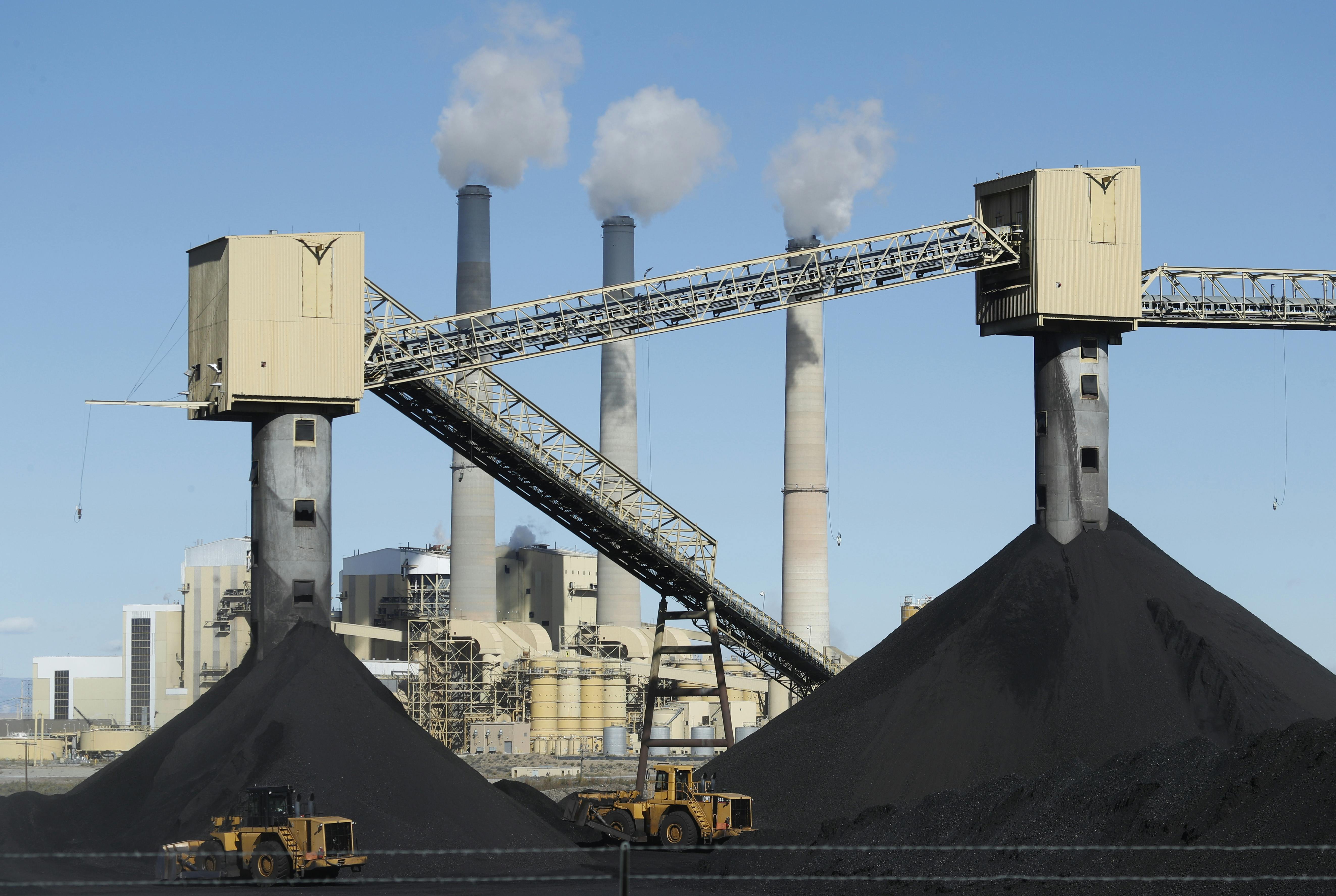 Piles of coal sit in front of a coal-fired power plant 