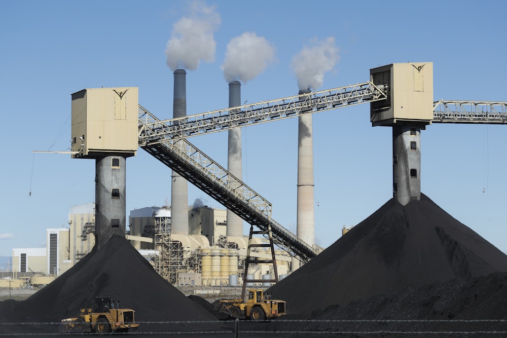 Piles of coal sit in front of a coal-fired power plant