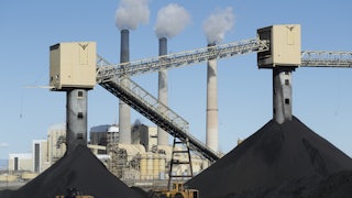 Piles of coal sit in front of a coal-fired power plant