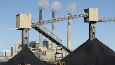 Piles of coal sit in front of a coal-fired power plant