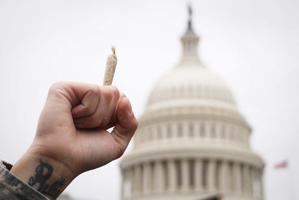 A man holds a joint in the air in front of the Capitol dome in Washington DC.
