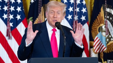 Donald Trump holds up both hands while speaking at a podium