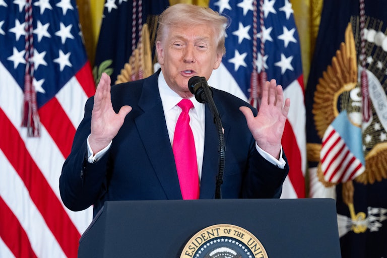 Donald Trump holds up both hands while speaking at a podium