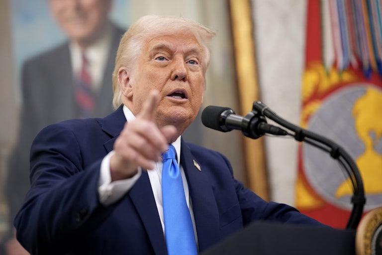 Donald Trump points a finger while speaking at a podium.