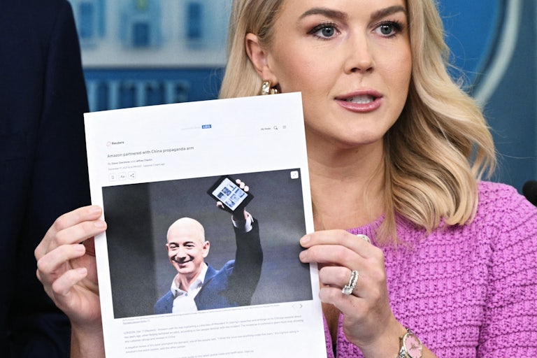 White House Press Secretary Karoline Leavitt holds up a printout of an article about Amazon owner Jeff Bezos during a press briefing