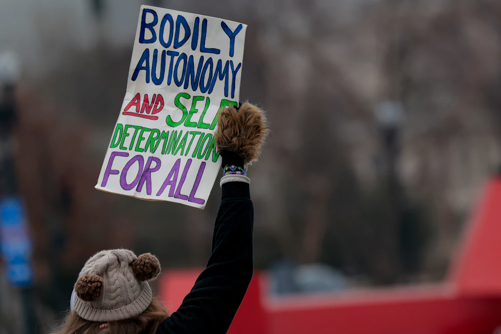 A woman lifts a sign saying "Bodily autonomy and self-determination for all" at a February protest in Washington, D.C., against the Trump administration’s anti-trans policies.
