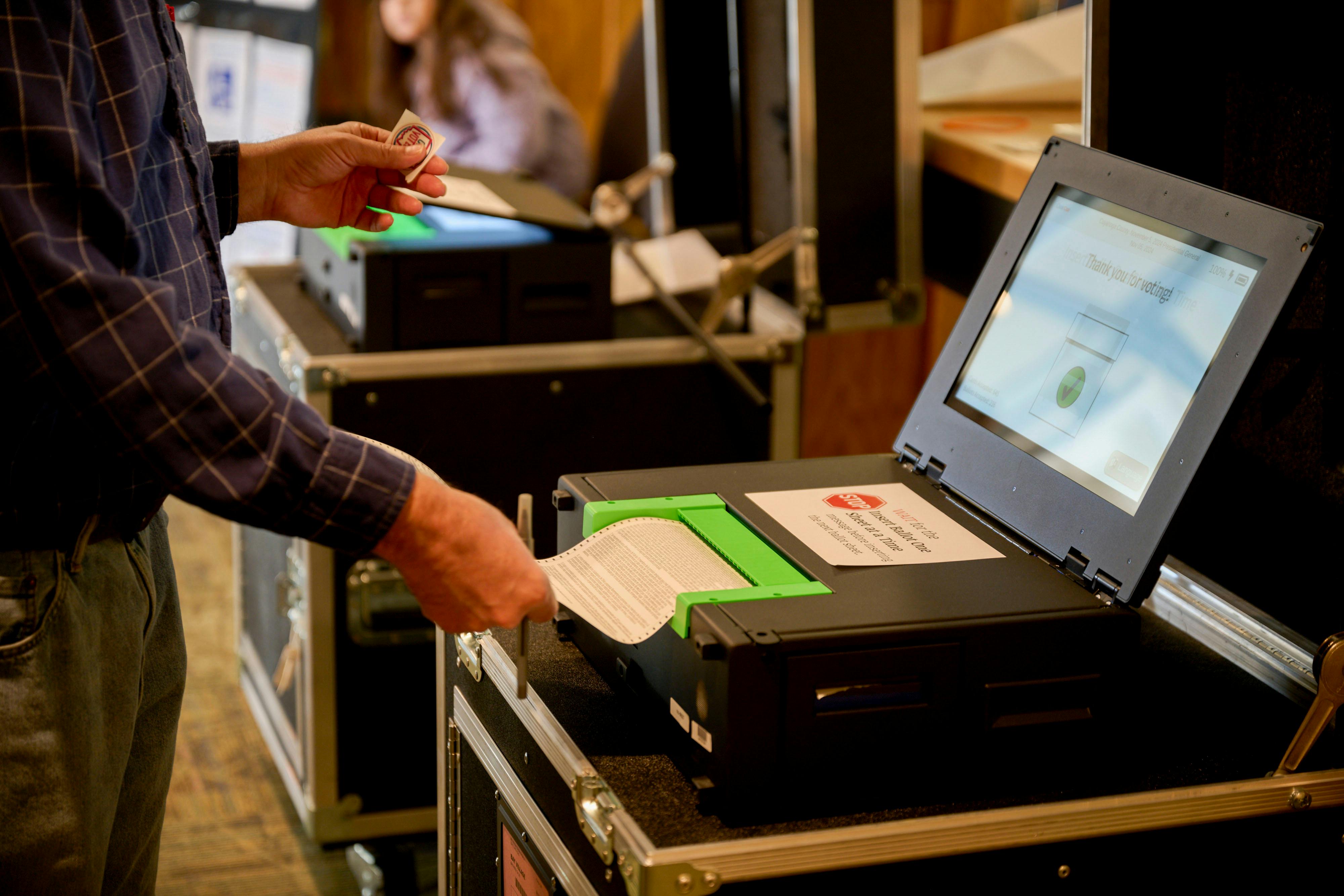 A man submits his ballot into a the voting machine.