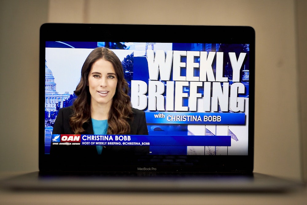 A laptop computer shows Christian Bobb and the words "Weekly Briefing with Christina Bobb" on OANN.