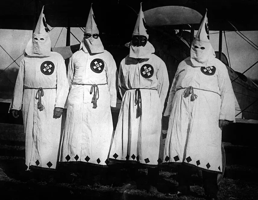 Black and white photograph of four masked Ku Klux Klan members in white robes and pointed hoods