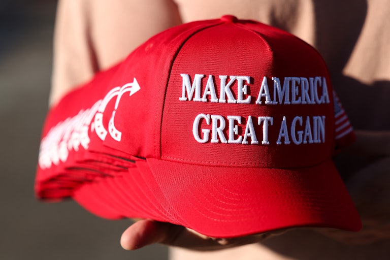 A person holds a stack of Make America Great Again hats.