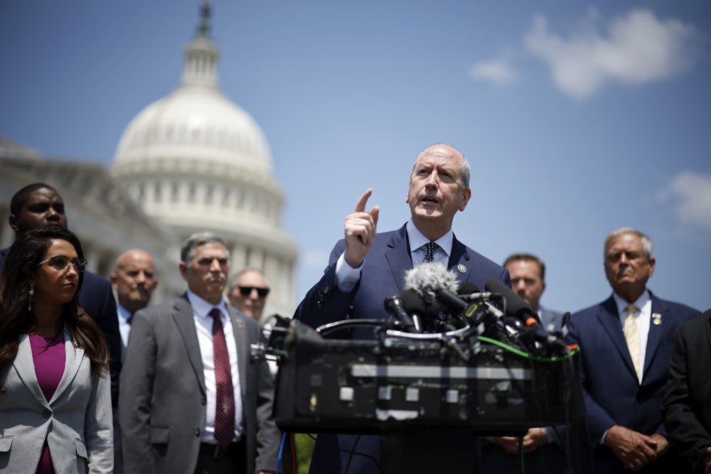 Dan Bishop speaks at a podium with other Freedom Caucus members and the U.S. Capitol in the background.