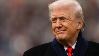 Donald Trump smiles at the camera at a sports event.