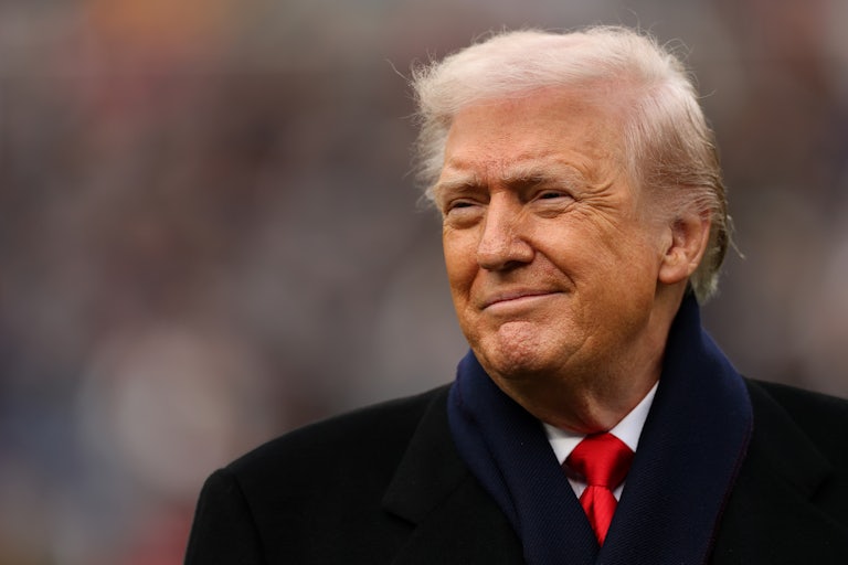 Donald Trump smiles at the camera at a sports event.