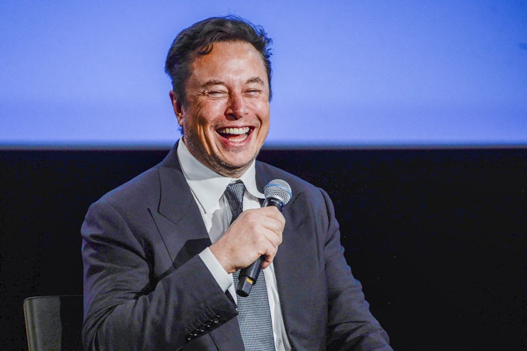Elon Musk laughing and holding a mic