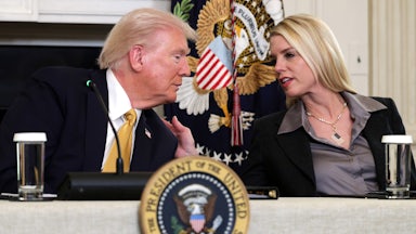Attorney General Pam Bondi leans over to speak with Donald Trump, placing a hand on his shoulder.