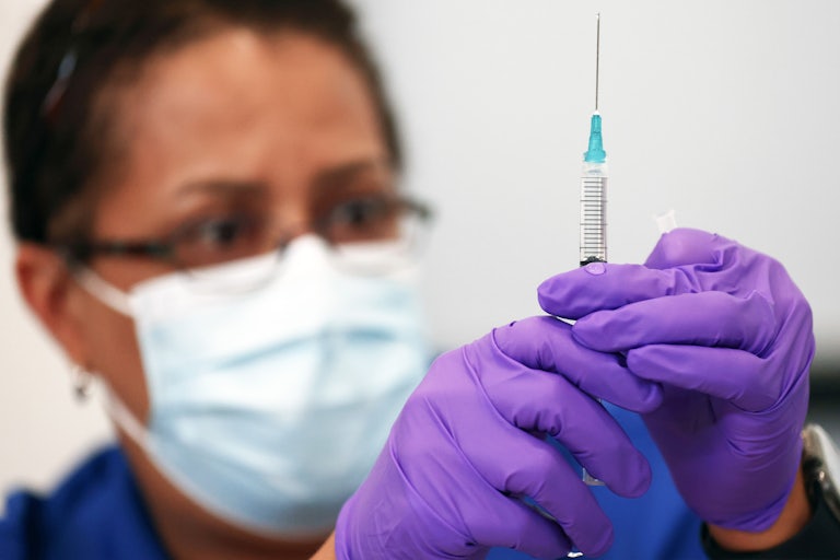 A close-up of a pharmacist’s hands as she prepares a Covid vaccine dose