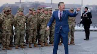 Defense Secretary Pete Hegseth points while soldiers stand in the background.