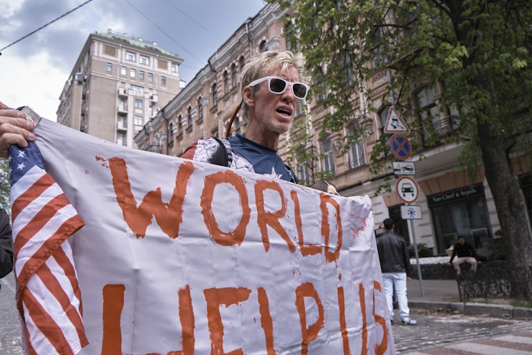 Donald Trump’s attempted assassin Ryan Routh holds a banner that says, "World help us" while walking in Kyiv