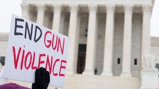 A person holds a sign reading "End Gun Violence" on the steps of the Supreme Court.